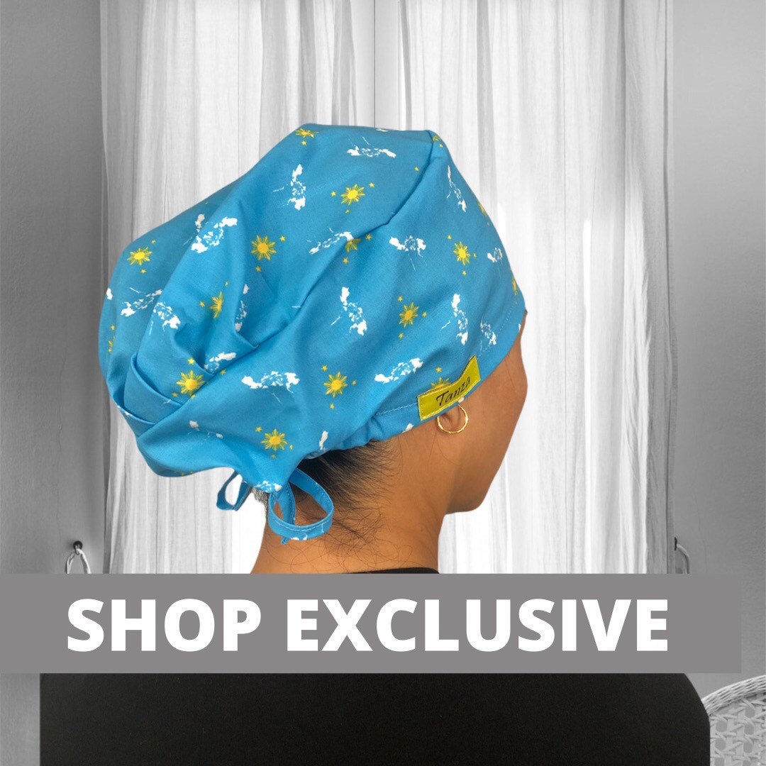 A person wearing a teal scrub cap with yellow sun and star designs, reminiscent of the Philippine flag's symbols.