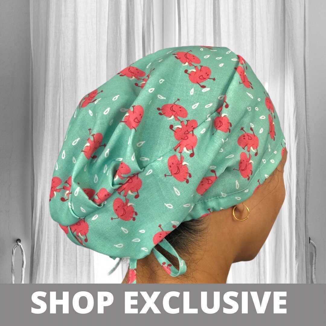 A soft scrub cap featuring a playful pattern of pink cartoon kidneys on a light teal background.