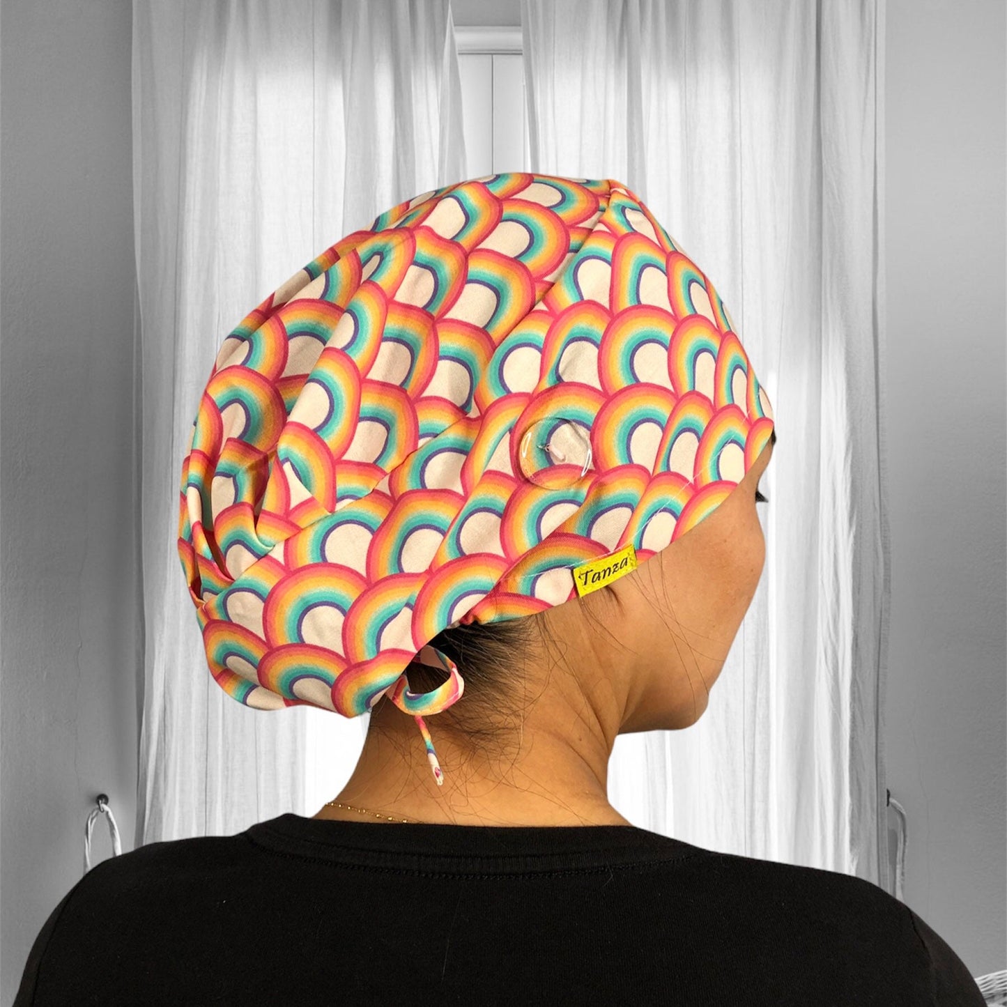 A vibrant, rainbow-patterned scrub cap that features overlapping arches in shades of red, orange, yellow, green, blue, and purple.