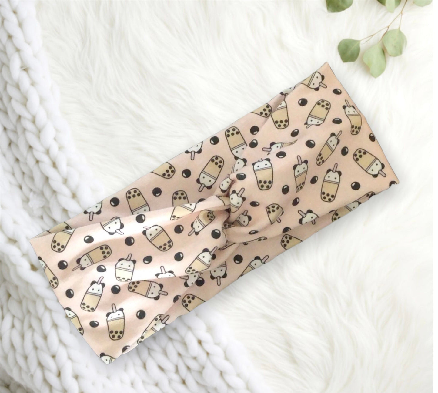 A beige fabric headband featuring a playful pattern with cartoon bubble tea cups and black tapioca pearls.