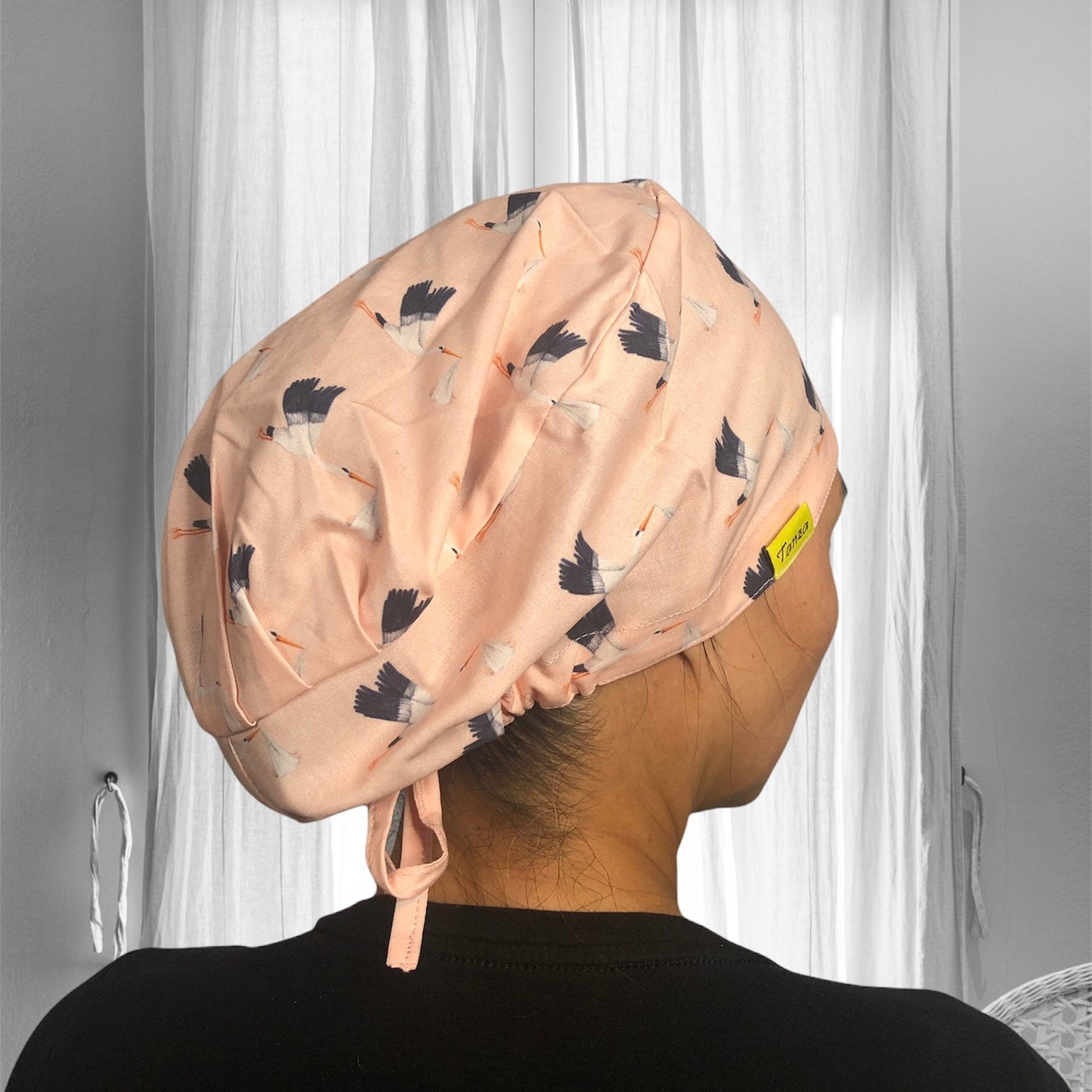 A stylish head cap featuring a peach-colored fabric adorned with a pattern of flying birds.