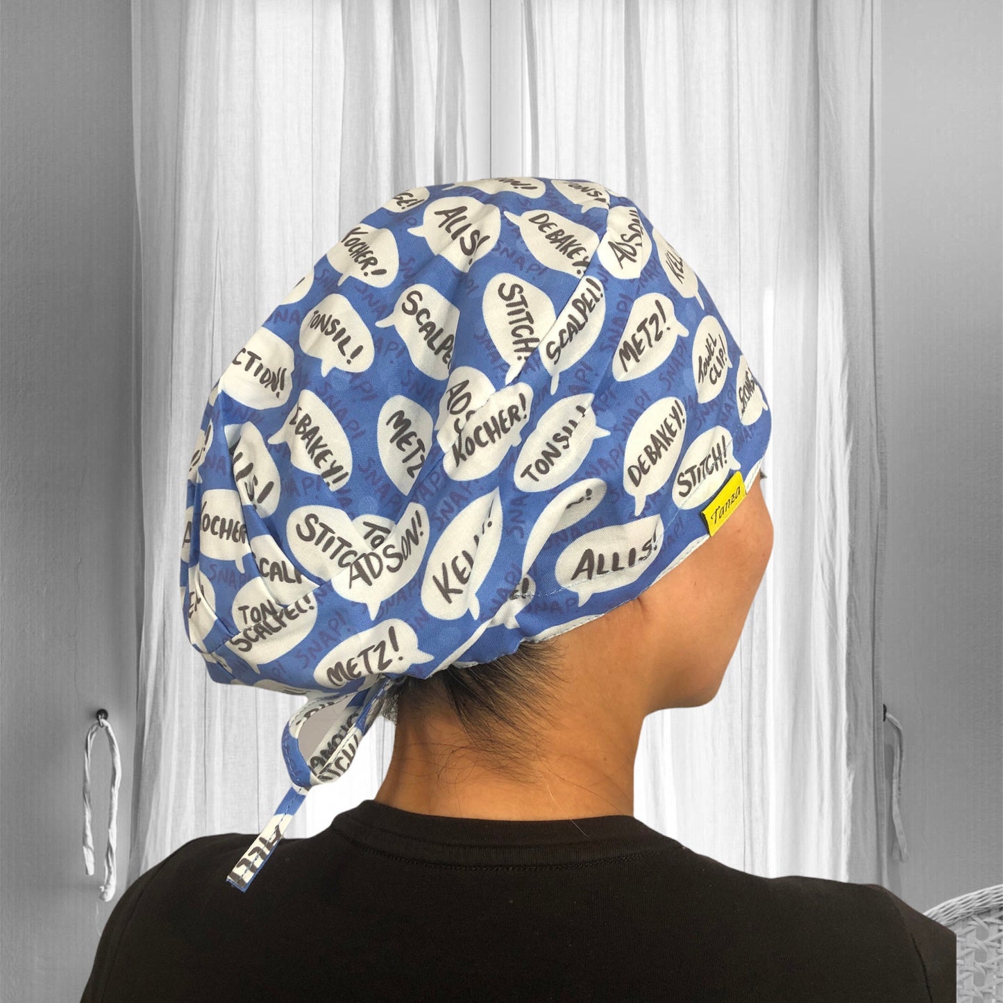 A person wearing a blue scrub cap with white speech bubbles containing words like "Scalpel!", "Metz!", "Stitch!", and other surgical terms.