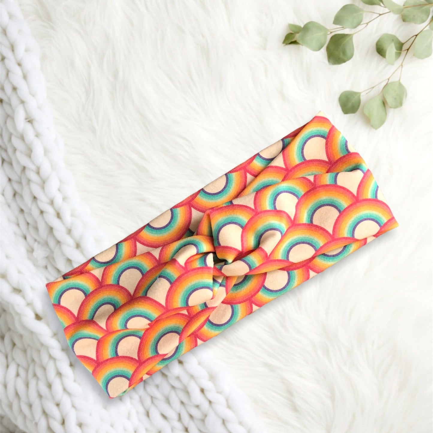 A vibrant, rainbow-patterned headband that features overlapping arches in shades of red, orange, yellow, green, blue, and purple.