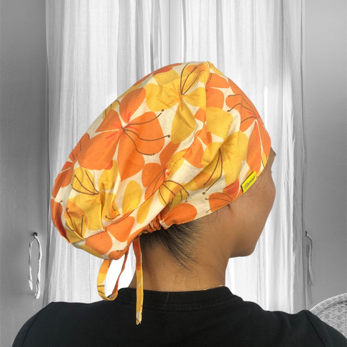 A colorful scrub cap with a vibrant floral pattern in shades of orange and yellow.