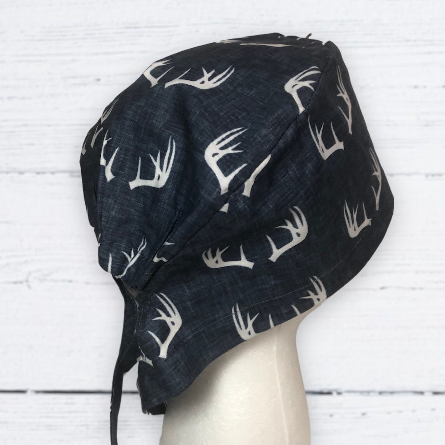 A dark scrub cap featuring a pattern of white antler designs.