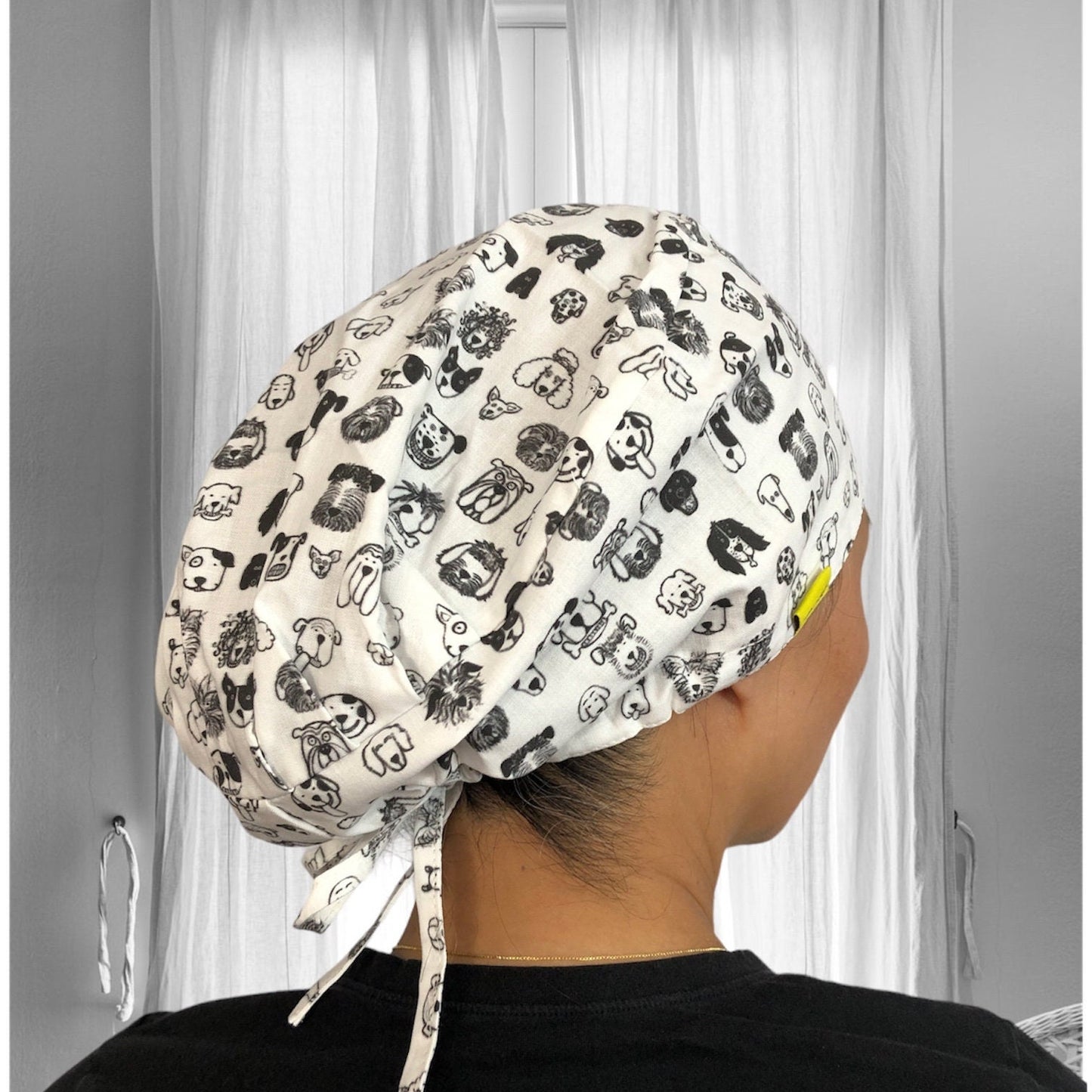 A scrub cap covered in a black and white print featuring various cute animal faces.