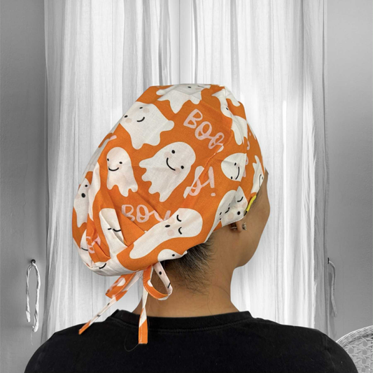 A person wearing an orange scrub cap with ghost patterns.