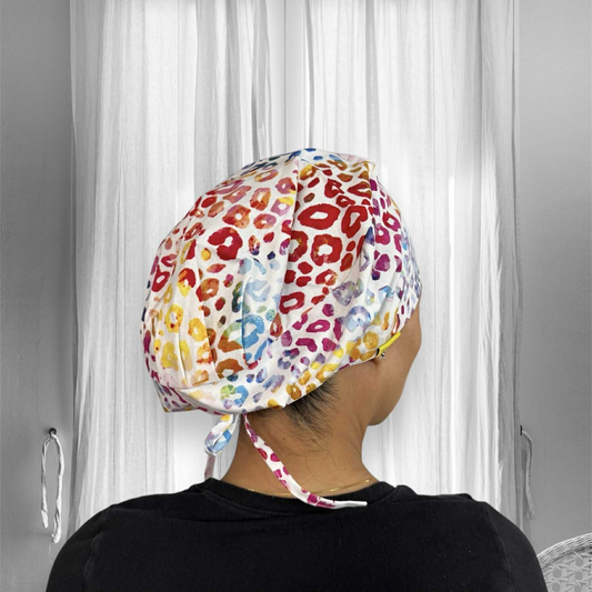 A person wearing a colorful rainbow cheetah print scrub cap.