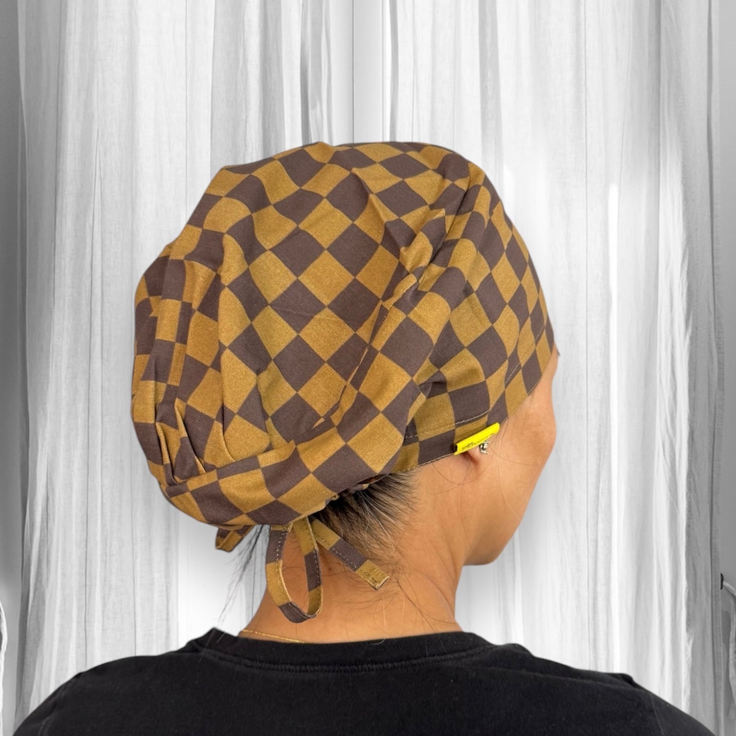 A brown and yellow checkered scrub cap with ties at the back.
