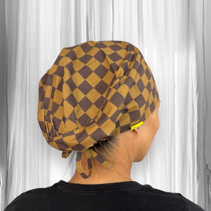 A brown and yellow checkered scrub cap with ties at the back.