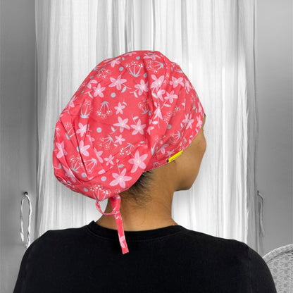 A red cap adorned with a floral pattern featuring pink flowers and light blue dots.