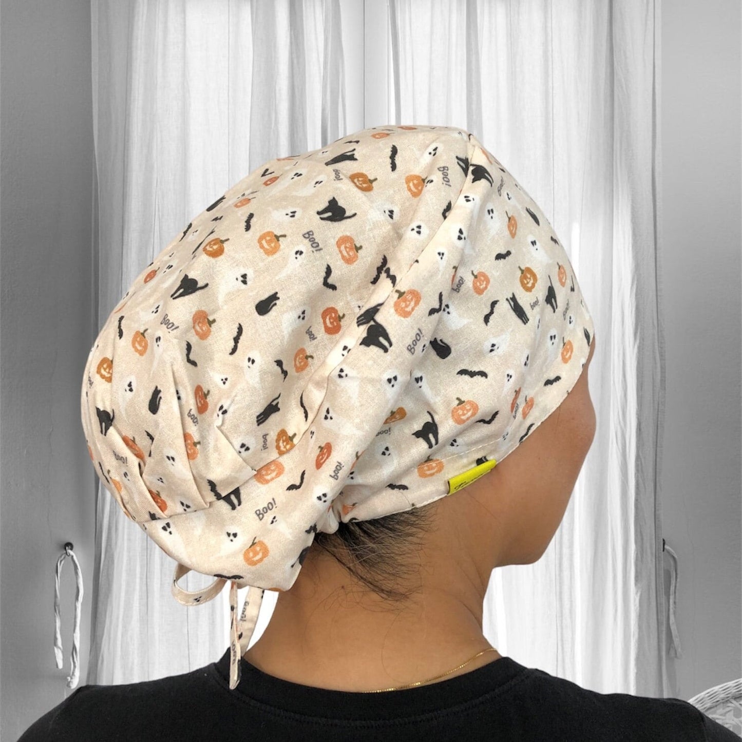 pleated Euro Scrub Caps with Black cat silhoutte, halloween pumpkin in orange, ghost, Boo word on beige background.